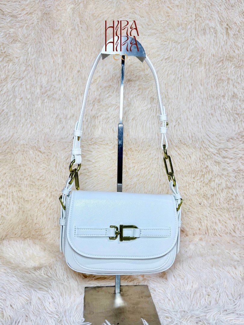 Charles & Keith White Saddle Bag with Gold Hardware (Category: Luxury Bags & Wallets) located in Caloocan City. Submitted by hirahira.co (Listing ID 1467278279, Image 2). Description: - Brand: Charles & Keith - Color: Clean White - Closure: Flap with gold-toned buckle detail - Strap: Adjustable with a chunky gold chain accent - Interior: Fabric-lined with a zippered pocket and brand tag - Condition: Excellent, structured silhouette with original 