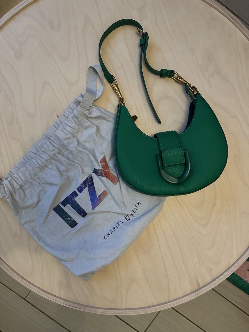Charles & Keith x Itzy Green Saddle Bag (Category: Shoulder Bags) located in San Pedro. Submitted by sweetcosmics (Listing ID 1467338250, Image 3). Description: - Authentic Charles & Keith x Itzy Collaboration Saddle Bag (Bought from SG) - Color: Vibrant green with chic gold-tone hardware - Design: Curved silhouette, front buckle detail, and embossed Itzy logo on the side gusset - Versatility: Includes an adjustable strap for comfortable wear - I