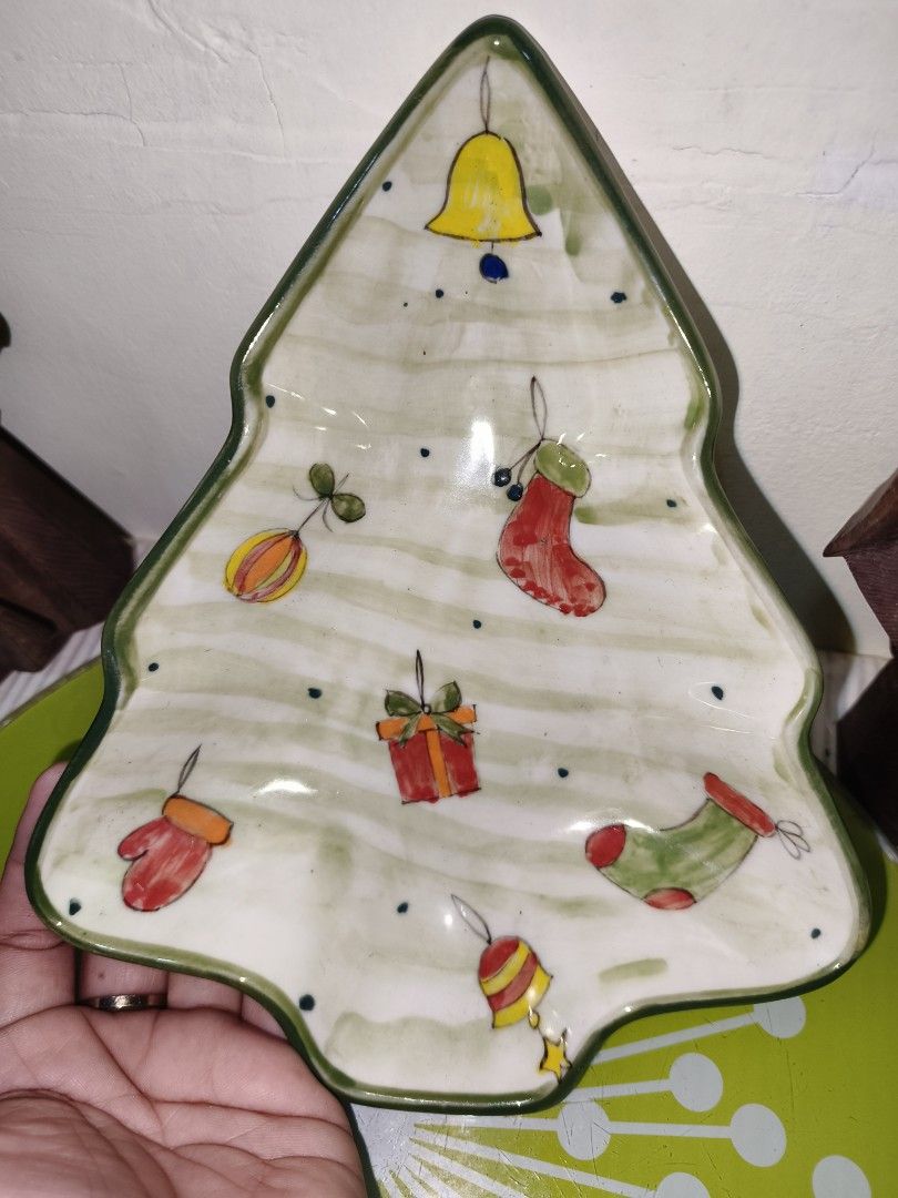 Christmas Tree Shaped Ceramic Dish Festive Serving Tray (Category: Dinnerware & Cutlery) located in Manila. Submitted by reascheyss51406 (Listing ID 1467170767, Image 2). Description: - Christmas tree-shaped ceramic serving dish - Features hand-painted holiday designs including bells, stockings, gift boxes, and mittens - Elegant green trim along the wavy edges - Smooth white glossy finish on both top and bottom - Ideal for serving holiday snacks,