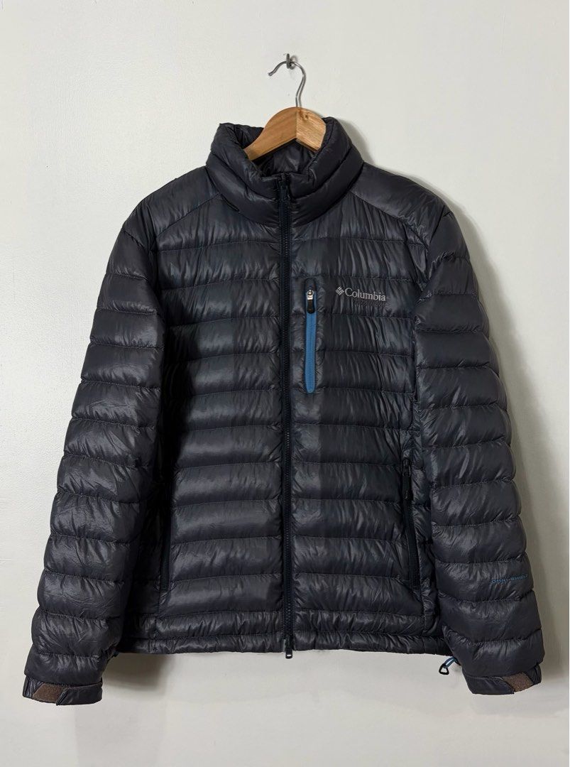 COLUMBIA OMNI-HEAT DOWN PUFFER JACKET (Category: Coats, Jackets and Outerwear) located in Cavite. Submitted by frankiemnla (Listing ID 1467324013, Image 2). Description: L- 27.5 W- 23 Size- M to L Excellent condition • Design: Lightweight horizontal puffer baffling with a full-length zipper. • Distinct Details: Features a signature vertical zippered chest pocket highlighted by a contrasting blue accent outline, matching the dark charcoal/navy blu