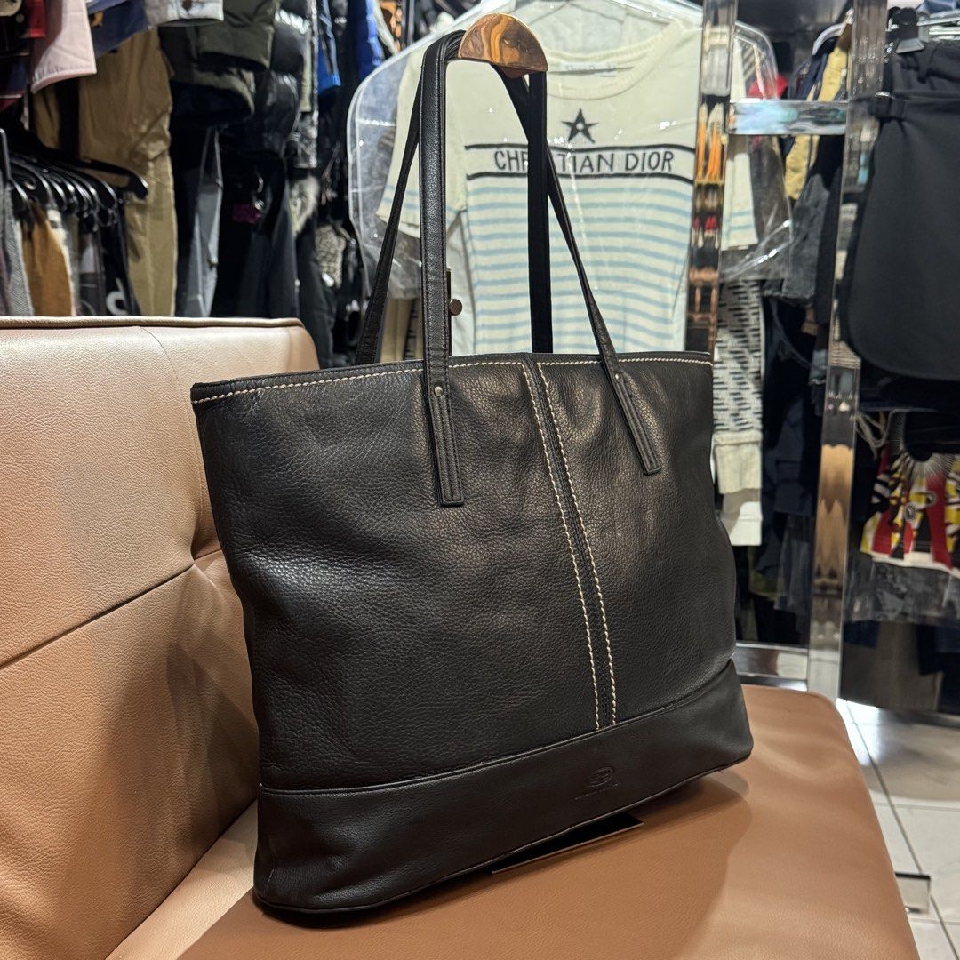 COMO Black Genuine Leather Tote Bag (Category: Tote Bags) located in Rizal. Submitted by houseofbell (Listing ID 1467360642, Image 2). Description: - Brand: COMO - Color/Material: Black leather with grainy texture - Design: Contrast stitching down the middle and embossed logo branding - Storage: Spacious main compartment and exterior back zip pocket - Straps: Dual shoulder straps - Hardware: Solid hardware details throughout Dimension: 16x12 inch