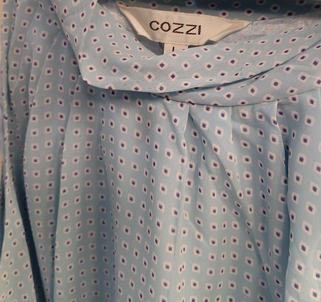 Cozzi Blue Geometric Print Sleeveless Halter Blouse (Category: Sleeveless) located in Kananga. Submitted by aurylien.clo (Listing ID 1467189391, Image 3). Description: - Brand: Cozzi - Dimes: L- 26, B- 28, W-30 - Size: L - Color/Pattern: Blue with small geometric square print - Neckline: Halter neck with side tie bow - Details: Pleated front drape - Fabric: Lightweight and comfortable.
