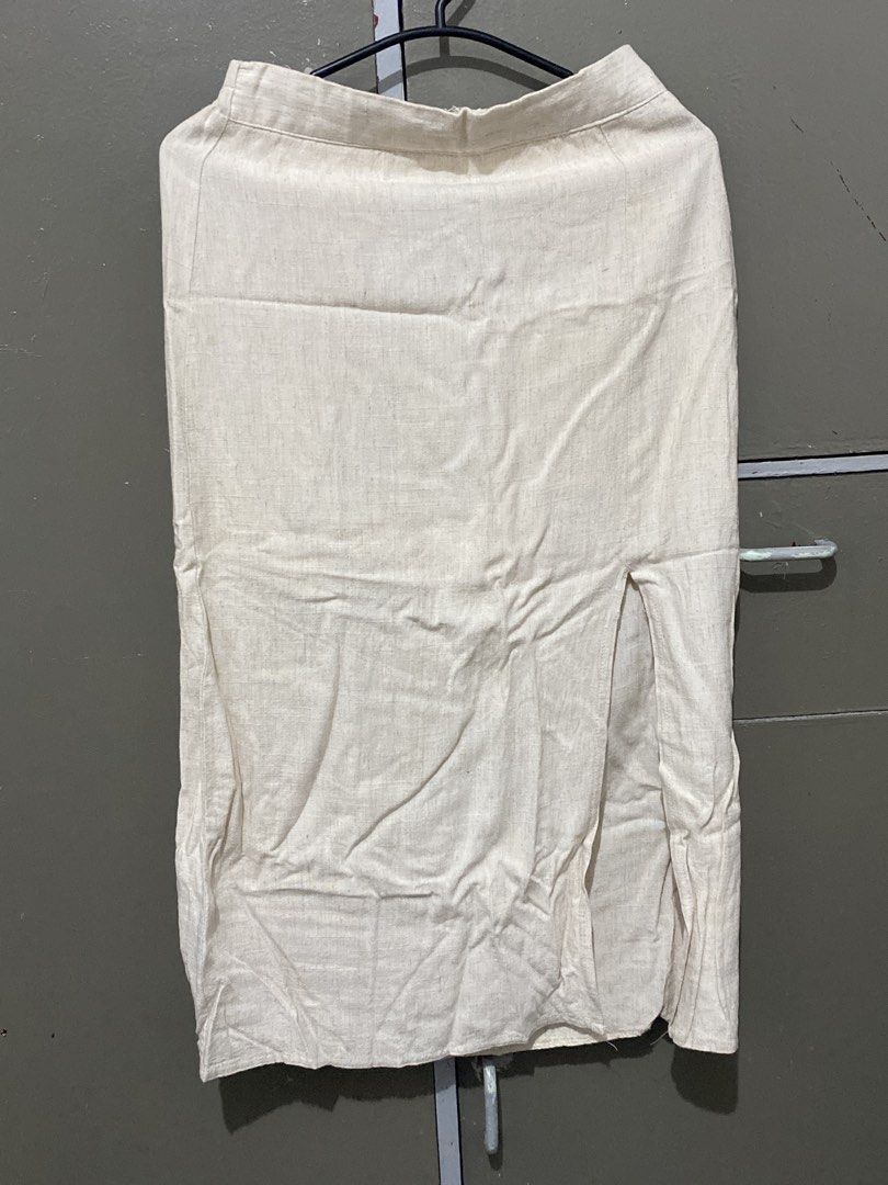 Cream Long Skirt with Front Slit (Category: Skirts) located in Manila. Submitted by e071803 (Listing ID 1467250676, Image 1). Description: - Color: Neutral cream/beige - Material: Lightweight woven fabric - Fit: High waist with structured waistband, straight silhouette (midi to maxi length) - Feature: Front slit for easy movement - Condition: Needs ironing due to storage wrinkles - Versatility: Easily matches any basic top.