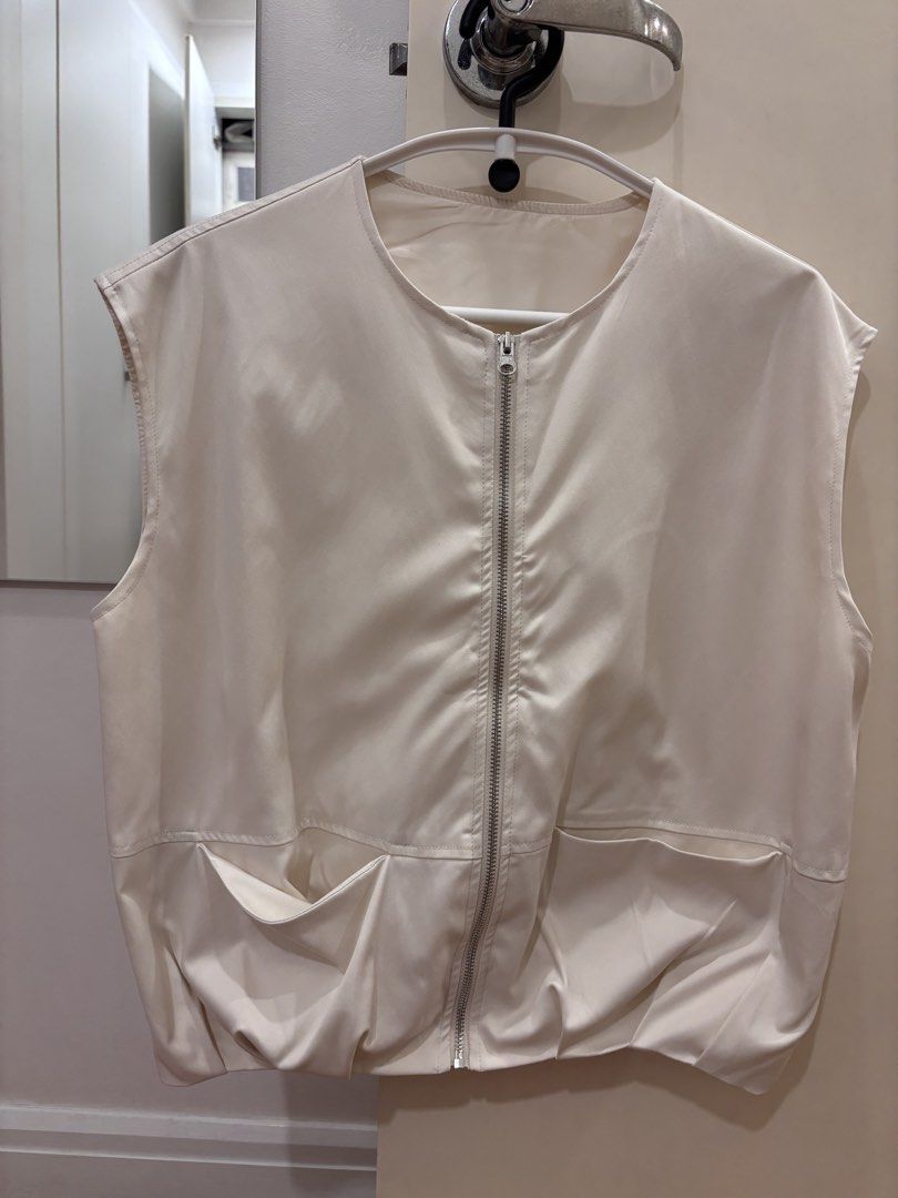 Cream Sleeveless Zip-Up Vest with Pockets (Category: Sleeveless) located in Makati City. Submitted by camdeclutters (Listing ID 1467298619, Image 1). Description: - Color: Neutral cream - Material: Lightweight and comfortable - Design: Full front zipper, round neckline, and sleeveless style - Features: Two front pockets and gathered hem for a subtle puffed shape - Styling: Easy to layer over tops and shirts - Condition: Clean and ready to wear.