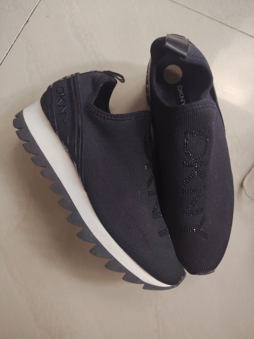 DKNY Black Slip-On Platform Sneakers (Category: Sneakers) located in Tanza. Submitted by kath172 (Listing ID 1467240181, Image 1). Description: - Brand: DKNY - Color: Black with white midsole and black jagged treads - Style: Slip-on sneakers with chunky ridged soles - Material: Stretchy fabric upper - Details: Eye-catching rhinestone DKNY logo lettering down the front - Convenience: Heel pull tab for easy on and off - Condition: Super comfortable