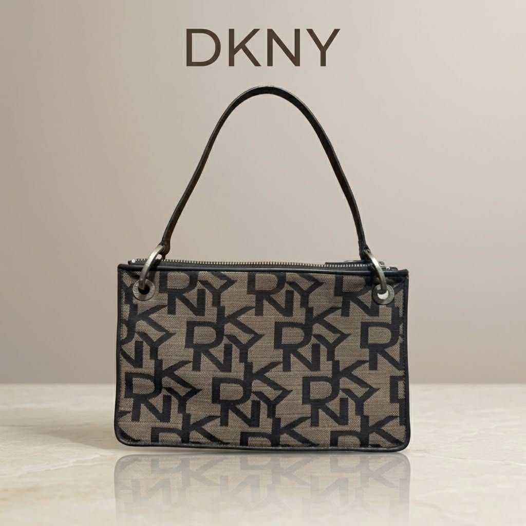 DKNY Monogram Shoulder Bag Brown Black (Category: Luxury Bags & Wallets) located in Carmen. Submitted by rr_thrifts (Listing ID 1467289334, Image 1). Description: - Brand: DKNY - Material: Brown and black monogram canvas with black leather trim - Closure: Top zip closure with leather pull tab - Interior: Beige fabric lining with a zippered pocket and DKNY logo patch - Strap: Single black leather strap with silver-tone hardware - Flaw Notice: Heav
