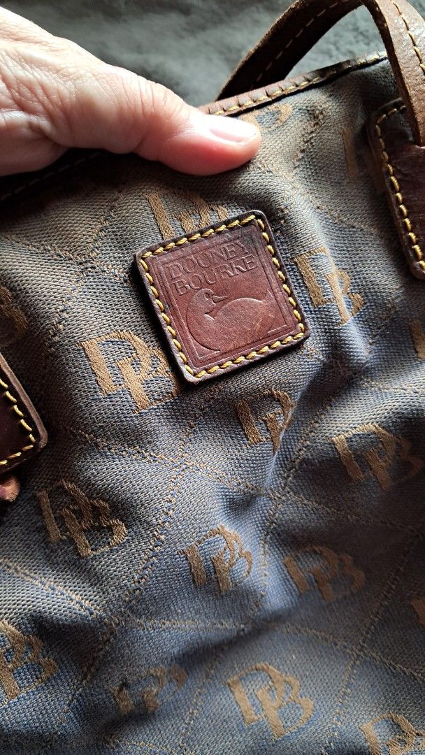 Sold>Dooney & Bourke Monogram Canvas Shoulder Bag with Tassels (Category: Luxury Bags & Wallets) located in Cavite. Submitted by naning049 (Listing ID 1467182792, Image 1). Description: - Brown canvas shoulder bag with allover DB monogram print - Dark brown leather handles and trim with matching side tassel charms - Front leather logo patch and protective metal feet on the base - Spacious interior with a structured quilted exterior design PROJECT