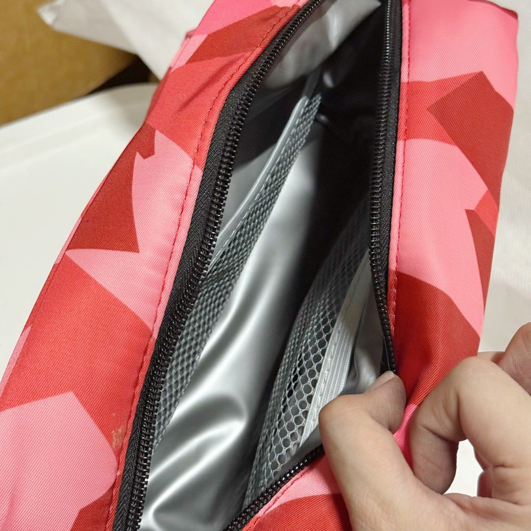 Dula Pink Camo Pouch Makeup Bag (Category: Purses & Pouches) located in Marikina City. Submitted by lovegoeson (Listing ID 1467265021, Image 2). Description: - Brand: Dula - Design: Bold pink, red, and rose camouflage pattern with embroidered black logo - Interior: Silver insulated lining with convenient side mesh pockets - Closure: Secure top zip - Extras: Includes a small side strap for easy carrying - Versatile Use: Great for organizing makeup