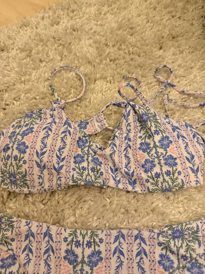 Floral Print Two-Piece Bikini Set (Category: Bikinis & Swimsuits) located in Mandaluyong City. Submitted by riz_040521 (Listing ID 1467208038, Image 2). Description: Worn once!! - Style: Matching two-piece bikini - Pattern: Blue and pink floral on white background - Top: Adjustable shoulder straps with trendy front cutout details - Bottoms: Standard cheeky cut with matching print - Condition: Clean fabric, perfect for the beach or pool days.