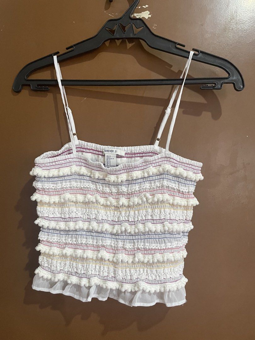 Forever 21 White Smocked Crop Top Size S (Category: Blouses) located in Manila. Submitted by mochi_dear (Listing ID 1467211755, Image 1). Description: - Brand: Forever 21 - Size: S - Color: White with colorful stitching details - Features: Pom-pom trim rows down the front, adjustable spaghetti straps, and a ruffled hem - Material: Lightweight fabric, ideal for warm weather.