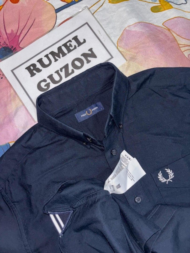 Fred Perry Navy Button-Down Long Sleeve Shirt (Category: Coats, Jackets and Outerwear) located in Quezon City. Submitted by rumel.guzon1630-15361 (Listing ID 1467191496, Image 1). Description: - Brand: Fred Perry - Color: Dark navy blue - Condition: like new with original tags attached - Details: Long sleeve, button-down front, classic collar - Accents: Signature embroidered laurel wreath logo on front pocket, contrasting white stripes on sleeve 