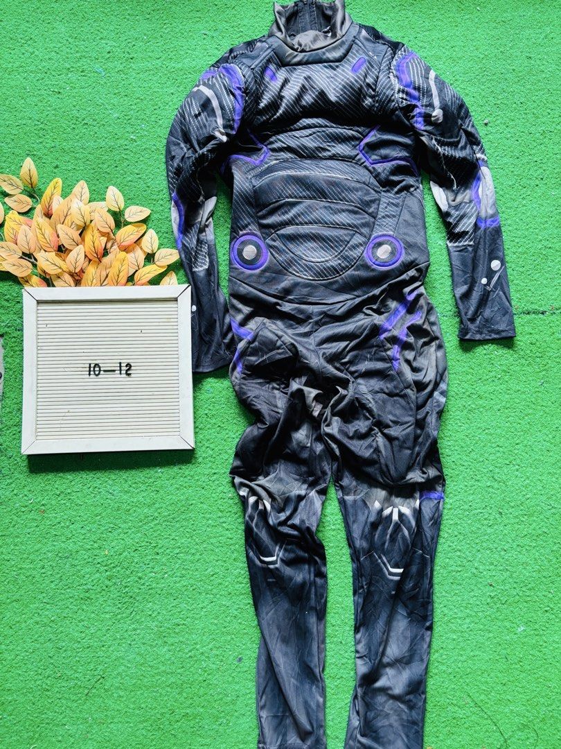 Futuristic Sci-Fi Superhero Costume Size 10-12 (Category: Babies & Kids Fashion) located in San Mateo. Submitted by ariakid47 (Listing ID 1467358810, Image 1). Description: - Sci-fi style jumpsuit in sleek black with vibrant purple and white detailing - Features a padded chest armor effect with cool circular accents - Long sleeves and full-length pants complete with printed armor graphics - Convenient back zipper closure for easy wear - Size: 10-