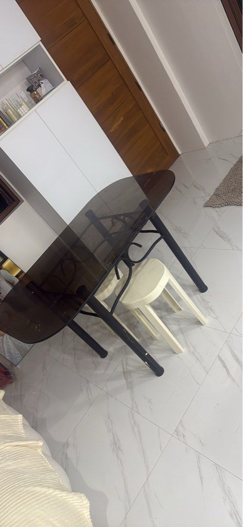 Glass Top Dining Table with 4 Stools (Category: Tables & Sets) located in Manila. Submitted by purpiecemanila (Listing ID 1467334241, Image 2). Description: - Sleek smoked glass top with a durable black metal frame and elegant scrollwork - Includes 4 cream-colored plastic stools that tuck neatly underneath to save space - Compact design, perfect for small kitchens, condos, or dining areas - Sturdy construction with minor, normal wear on surfaces 