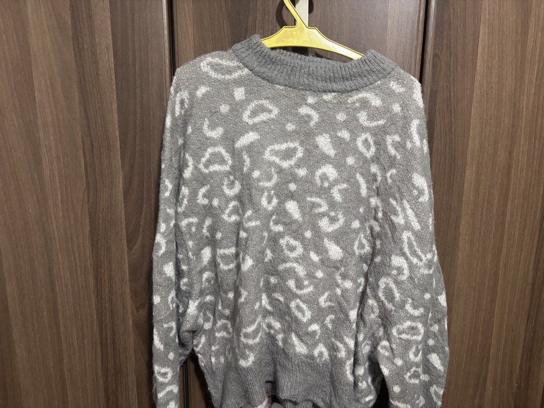 Grey leopard print knit sweater (Category: Longsleeves) located in Quezon City. Submitted by uniquebotique (Listing ID 1467347012, Image 2). Description: - Style: Grey knit sweater with all-over white leopard pattern - Fit: Relaxed, slightly oversized with a classic crewneck - Details: Ribbed cuffs and hem for a snug finish - Material: Soft and fluffy fabric, ideal for cooler weather - Versatility: Great for layering and easy to match with jeans 