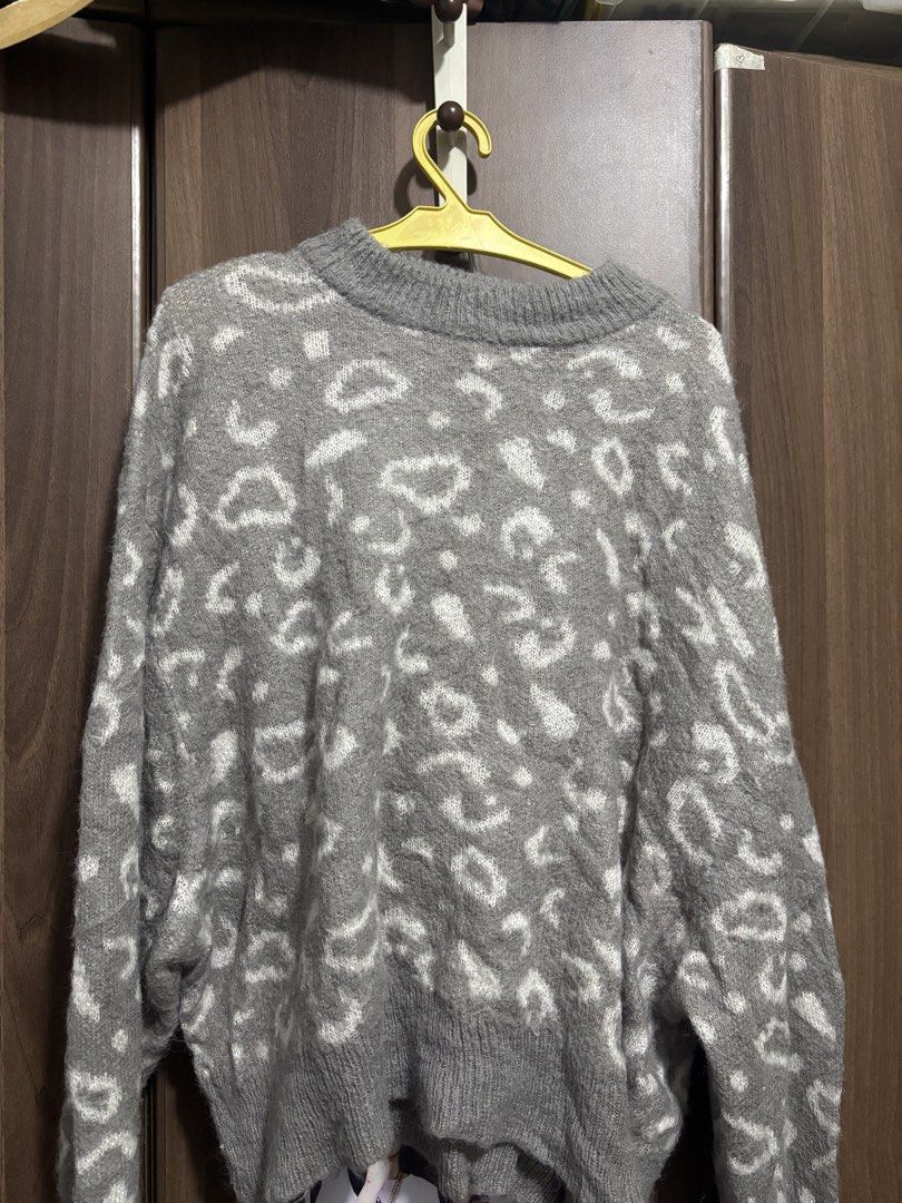 Grey leopard print knit sweater (Category: Longsleeves) located in Quezon City. Submitted by uniquebotique (Listing ID 1467347012, Image 1). Description: - Style: Grey knit sweater with all-over white leopard pattern - Fit: Relaxed, slightly oversized with a classic crewneck - Details: Ribbed cuffs and hem for a snug finish - Material: Soft and fluffy fabric, ideal for cooler weather - Versatility: Great for layering and easy to match with jeans 