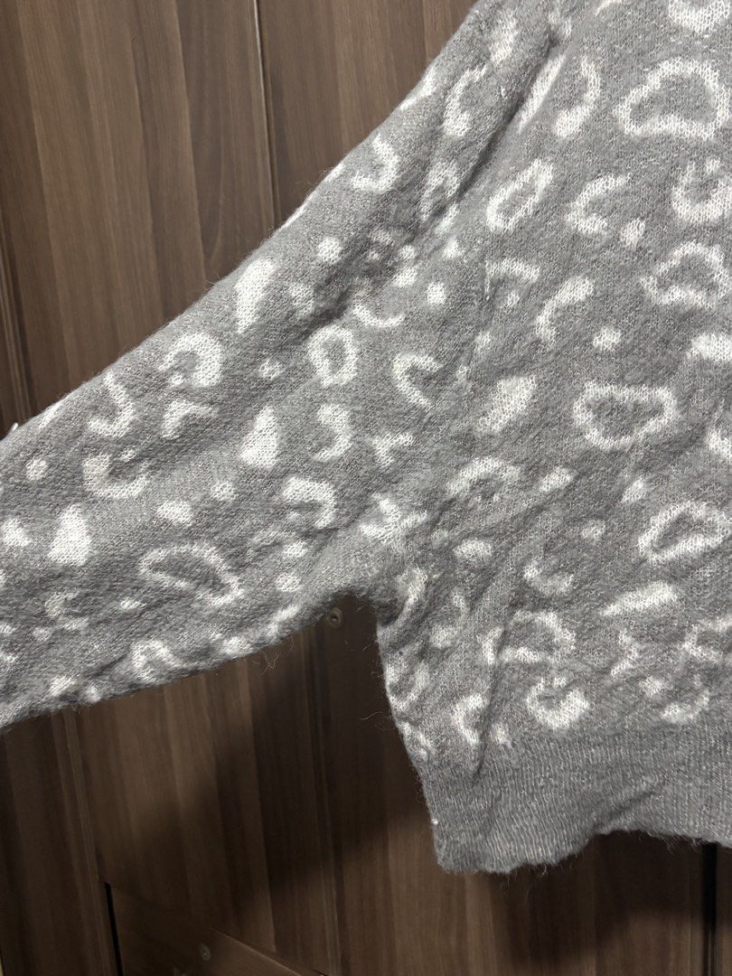 Grey leopard print knit sweater (Category: Longsleeves) located in Quezon City. Submitted by uniquebotique (Listing ID 1467347012, Image 3). Description: - Style: Grey knit sweater with all-over white leopard pattern - Fit: Relaxed, slightly oversized with a classic crewneck - Details: Ribbed cuffs and hem for a snug finish - Material: Soft and fluffy fabric, ideal for cooler weather - Versatility: Great for layering and easy to match with jeans 