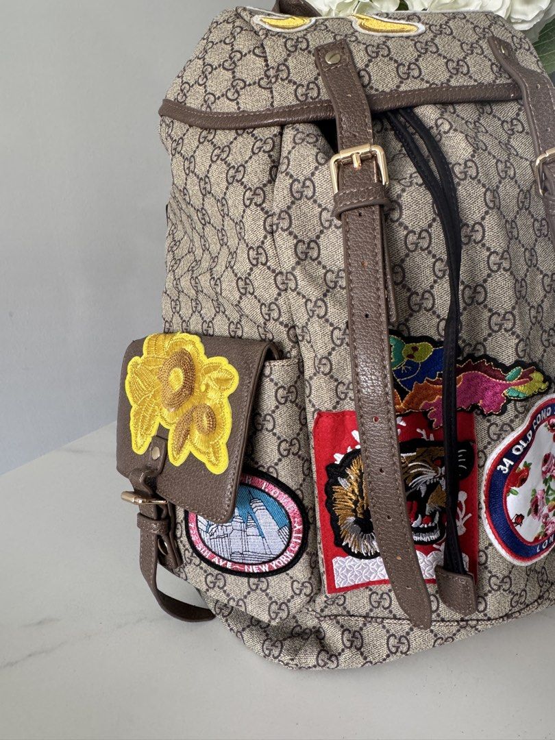 Canvas Patchwork Backpack (Category: Backpacks) located in Singapore. Submitted by rehomeedit (Listing ID 1467262238, Image 2). Description: - Backpack in iconic canvas - Features fun embroidered patches including a tiger, flowers, and Donald Duck - Brown leather trim and adjustable straps - Secure drawstring top closure with a buckle flap - Convenient side pockets with flap closures and snap buttons - Accented with the signature green and red We