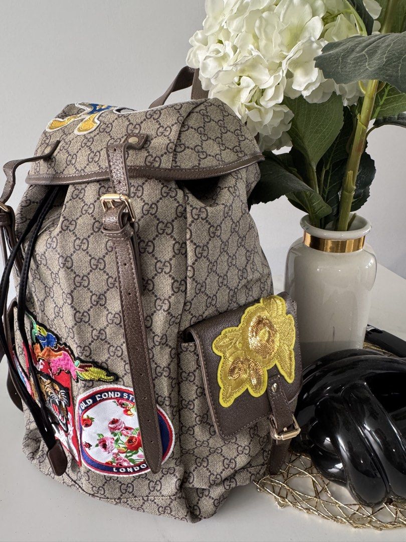 Canvas Patchwork Backpack (Category: Backpacks) located in Singapore. Submitted by rehomeedit (Listing ID 1467262238, Image 3). Description: - Backpack in iconic canvas - Features fun embroidered patches including a tiger, flowers, and Donald Duck - Brown leather trim and adjustable straps - Secure drawstring top closure with a buckle flap - Convenient side pockets with flap closures and snap buttons - Accented with the signature green and red We