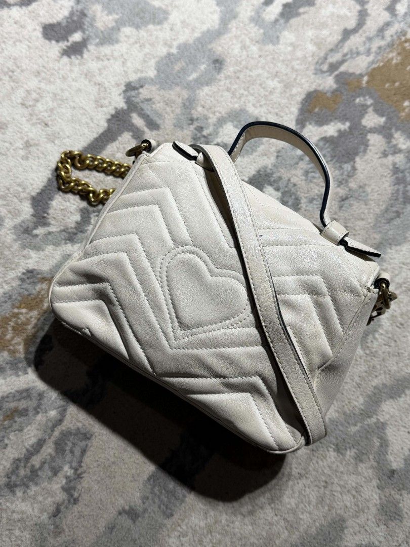 Gucci white Marmont Bag (Category: Luxury Bags & Wallets) located in Dagupan City. Submitted by kiroshi12 (Listing ID 1467238433, Image 2). Description: Authentic White leather Gucci GG Marmont top handle bag. Chevron quilting pattern with antique gold-tone hardware. Double G hardware on the front. Heart quilt detail on the back. Single top handle and removable leather shoulder strap. Includes interior zipper pocket. Serial number 547260 520981 s