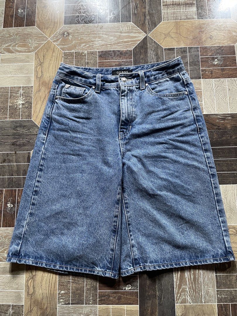 Guess Los Angeles Denim Shorts (Category: Jeans) located in Davao. Submitted by vin.my (Listing ID 1467202807, Image 1). Description: Guess denim shorts in mid-blue wash. High-waisted style with front button and zipper closure. Classic five-pocket layout including coin pocket with metal triangle logo. Back pocket features silver Guess triangle plaque and brown leather logo patch on the waistband. Heavy stonewash finish with traditional contrast s