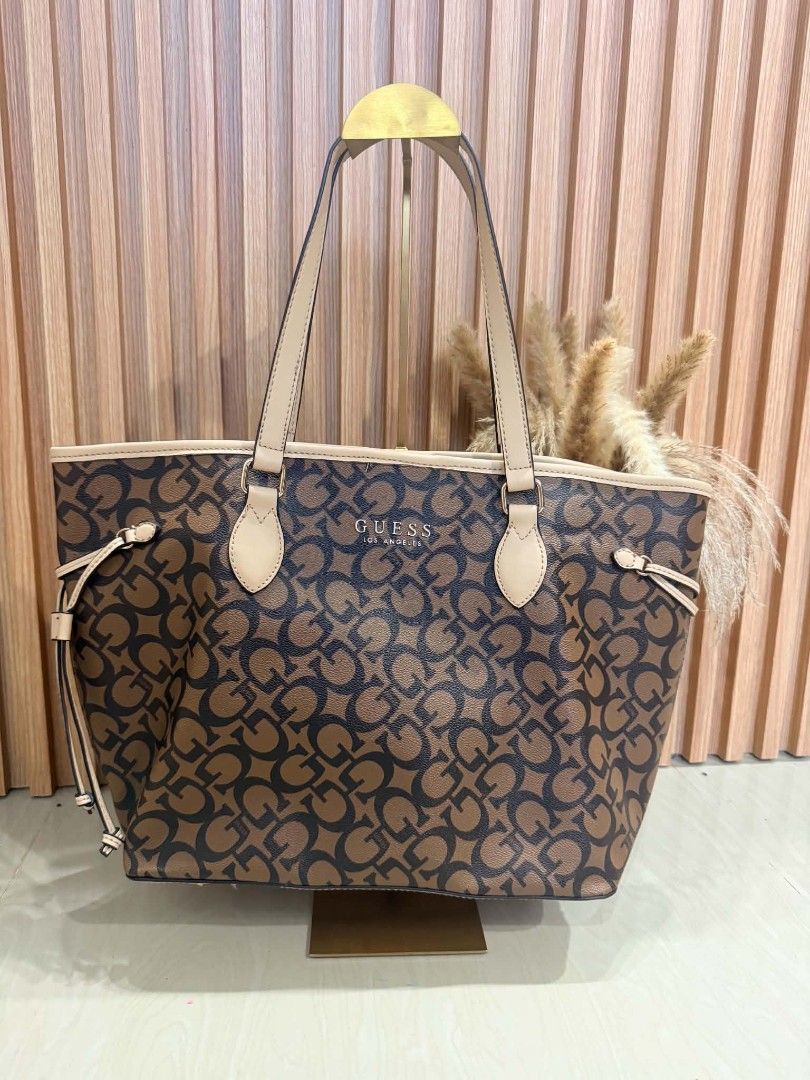 Guess Los Angeles Monogram Tote Bag (Category: Tote Bags) located in Pinamalayan. Submitted by chay0921 (Listing ID 1467282217, Image 1). Description: - Authentic Guess tote bag in classic brown and black monogram print - Elegant cream-colored shoulder straps and trim with gold-tone hardware - Adjustable side drawstrings to change the bag's shape - Secure magnetic snap top closure - Spacious interior lined with Guess logo pattern - Includes conve