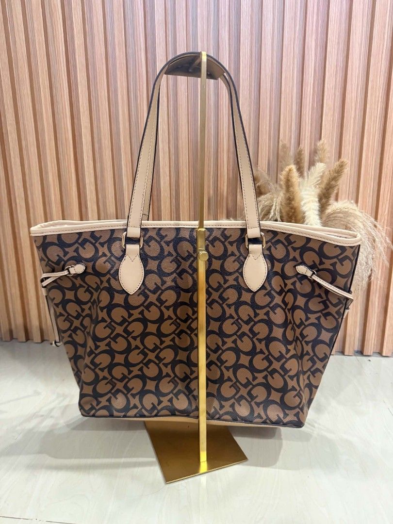 Guess Los Angeles Monogram Tote Bag (Category: Tote Bags) located in Pinamalayan. Submitted by chay0921 (Listing ID 1467282217, Image 2). Description: - Authentic Guess tote bag in classic brown and black monogram print - Elegant cream-colored shoulder straps and trim with gold-tone hardware - Adjustable side drawstrings to change the bag's shape - Secure magnetic snap top closure - Spacious interior lined with Guess logo pattern - Includes conve