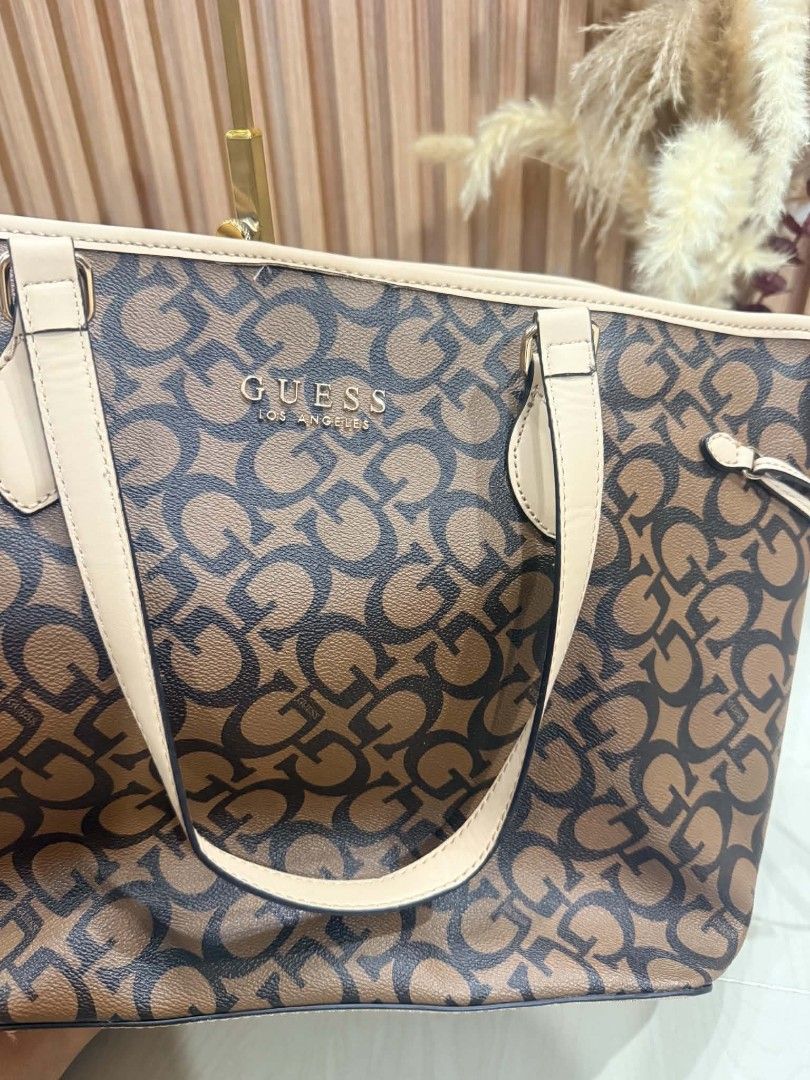 Guess Los Angeles Monogram Tote Bag (Category: Tote Bags) located in Pinamalayan. Submitted by chay0921 (Listing ID 1467282217, Image 3). Description: - Authentic Guess tote bag in classic brown and black monogram print - Elegant cream-colored shoulder straps and trim with gold-tone hardware - Adjustable side drawstrings to change the bag's shape - Secure magnetic snap top closure - Spacious interior lined with Guess logo pattern - Includes conve