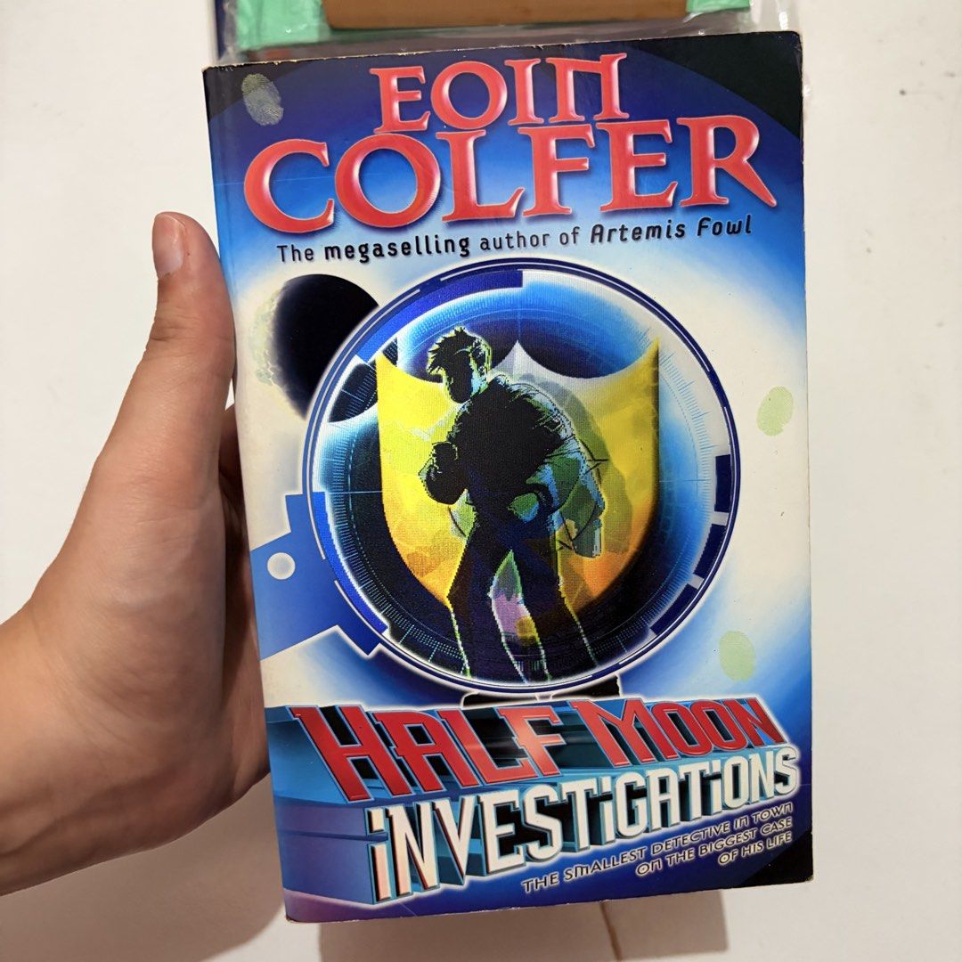 Half Moon Investigations by Eoin Colfer Paperback Book (Category: Storybooks) located in General Trias. Submitted by hayami.clo (Listing ID 1467289283, Image 1). Description: - Title: Half Moon Investigations - Author: Eoin Colfer (Creator of Artemis Fowl) - Publisher: Puffin - Format: Paperback - Condition: Standard shelf wear with yellowed pages - Synopsis: Follows Fletcher Moon, a pint-sized schoolboy and certified private investigator solving