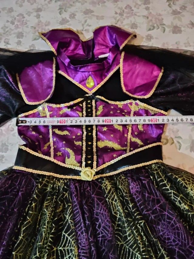 HALLOWEEN COSTUME (Category: Babies & Kids Fashion) located in Manila. Submitted by icamalicdem29 (Listing ID 1467174447, Image 2). Description: The image shows a children's Halloween costume, commonly sold by brands like Teetot & Co. or via retailers like Costco, featuring a black, purple, and green witch or vampire design with a tiered spiderweb skirt, flared bat-wing sleeves, a structured collar, and a matching bat headband. no Head band 3/7 y