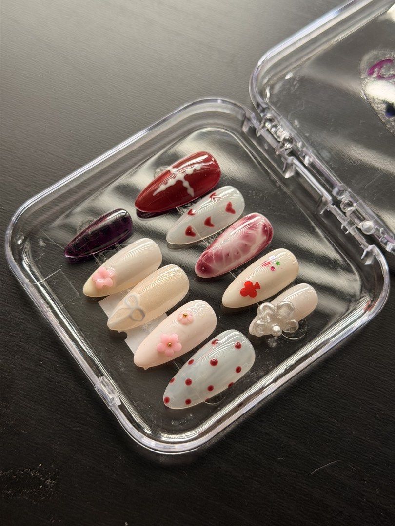 Handmade Press-On Nails Set Red White 3D Charms (SIZE L) (Category: Hands & Nails) located in Quezon City. Submitted by ninny.ph (Listing ID 1467190609, Image 1). Description: - Custom handmade press-on nail set in Almond shape - Chic mix of red, white, and dark purple polish - Detailed with 3D acrylic flowers, tiny red hearts, polka dots, silver bow charms, and marble effect - Includes a full set of 10 brand new, never worn nails - Neatly packed