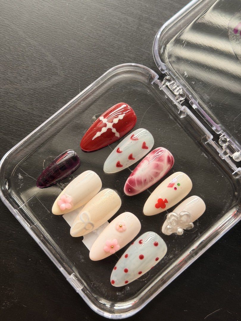 Handmade Press-On Nails Set Red White 3D Charms (SIZE L) (Category: Hands & Nails) located in Quezon City. Submitted by ninny.ph (Listing ID 1467190609, Image 3). Description: - Custom handmade press-on nail set in Almond shape - Chic mix of red, white, and dark purple polish - Detailed with 3D acrylic flowers, tiny red hearts, polka dots, silver bow charms, and marble effect - Includes a full set of 10 brand new, never worn nails - Neatly packed