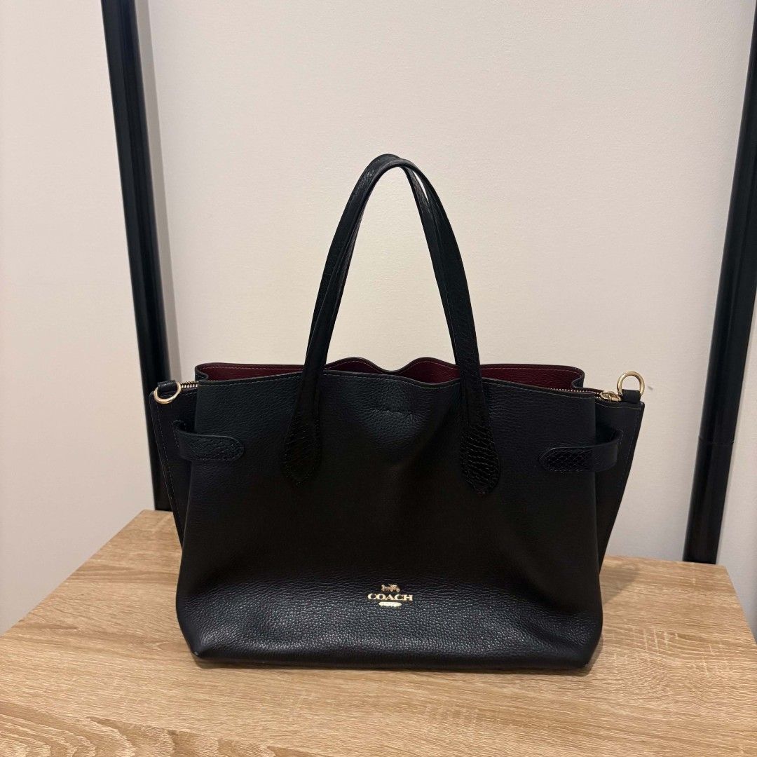 Coach Hanna Carryall Bag (Category: Luxury Bags & Wallets) located in Santa Rosa. Submitted by alfonsocadiz (Listing ID 1467174507, Image 3). Description: - Brand: Coach - Model: Hanna Carryall Bag - Color: Classic Black with rich burgundy interior lining - Material: Premium pebbled leather with subtle textured details - Features: Dual top handles, detachable and adjustable shoulder strap, secure center zip compartment, and gold-tone hardware - C