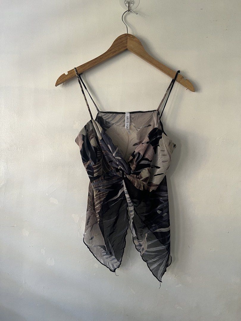 Haute Fox Tropical Print Camisole Top (Category: Sleeveless) located in Oroquieta. Submitted by zjstg (Listing ID 1467185111, Image 1). Description: - Brand/Style: Haute Fox tropical leaf camisole - Size: small - Design: Black, beige, and grey tropical print with a stylish front twist and unique asymmetrical hanky hem - Features: Sheer mesh fabric and thin adjustable straps - Versatility: Easy to throw on with jeans or shorts for warm weather -30