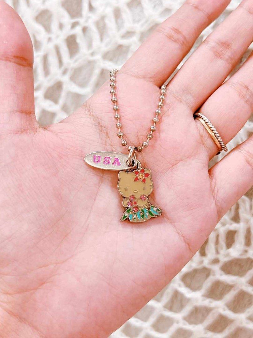 Hello Kitty USA Hula Dancer Pendant Necklace (Category: Necklaces) located in Manila. Submitted by janetecson05 (Listing ID 1467309279, Image 1). Description: - Adorable Kitty pendant wearing a festive hula outfit - Features colorful enamel detailing with a floral skirt and flower hair accent - Includes a separate pink-lettered USA stamped oval charm - Comes ready to wear on a classic silver-tone ball chain - Great gift idea or addition to any Sa
