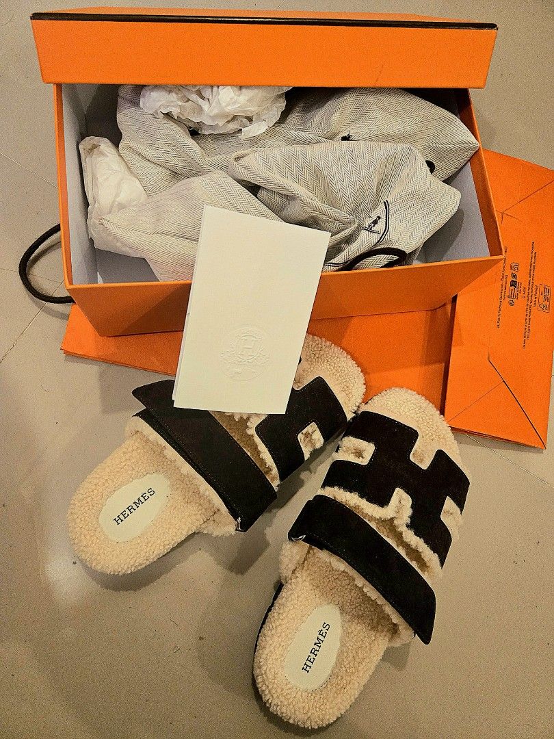 Hermès Chypre Sandals Dark Brown Shearling (Category: Sneakers & Footwear) located in Plaridel. Submitted by aucourant_fashion (Listing ID 1467218615, Image 3). Description: - Brand: Hermès - Model: Chypre Sandals - Color: Black and White Shearling - Condition: Pristine, zero wear on soles (Brand New in Box) - Features: Iconic H-strap design, adjustable velcro closure, soft fleece lining, branded insoles, dark grey rubber sole with signature chai