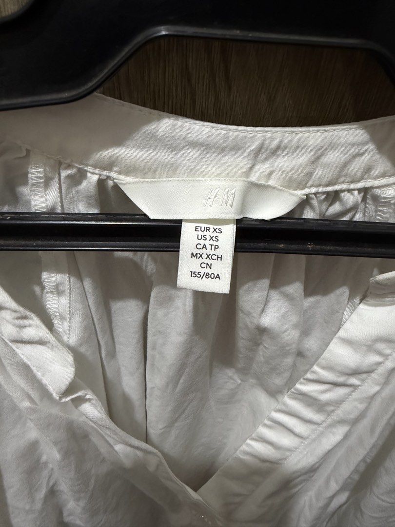H&M White Long Sleeves Deep V-Neck (Category: Blouses) located in Calamba. Submitted by nicalison (Listing ID 1467310966, Image 2). Description: - Brand: H&M - Size: XS (EUR/US sizing) - Color: Classic White - Design: V-neck collar with button-down front - Sleeves: Three-quarter puff sleeves with gathered cuffs - Fit: Relaxed, lightweight cotton material - Style: Minimalist basic, easy to pair with jeans or skirts for everyday wear.