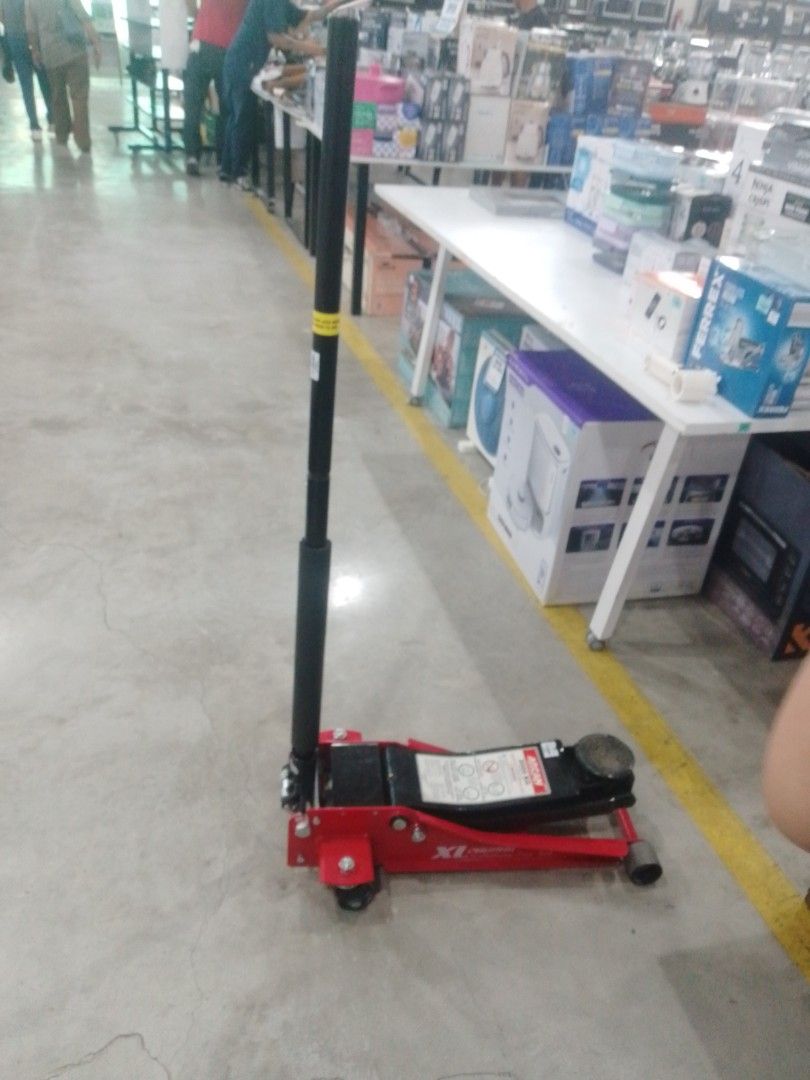Hydraulic Floor Jack (Category: Construction Tools & Equipment) located in Manila. Submitted by maryjane09. (Listing ID 1467207545, Image 1). Description: - Heavy-duty red and black hydraulic floor jack - Long handle lever included for easy lifting - Sturdy metal base with wheels for effortless mobility around the garage - Ideal and reliable tool for working under cars and trucks - Condition: Shows some dust from storage, fully functional.