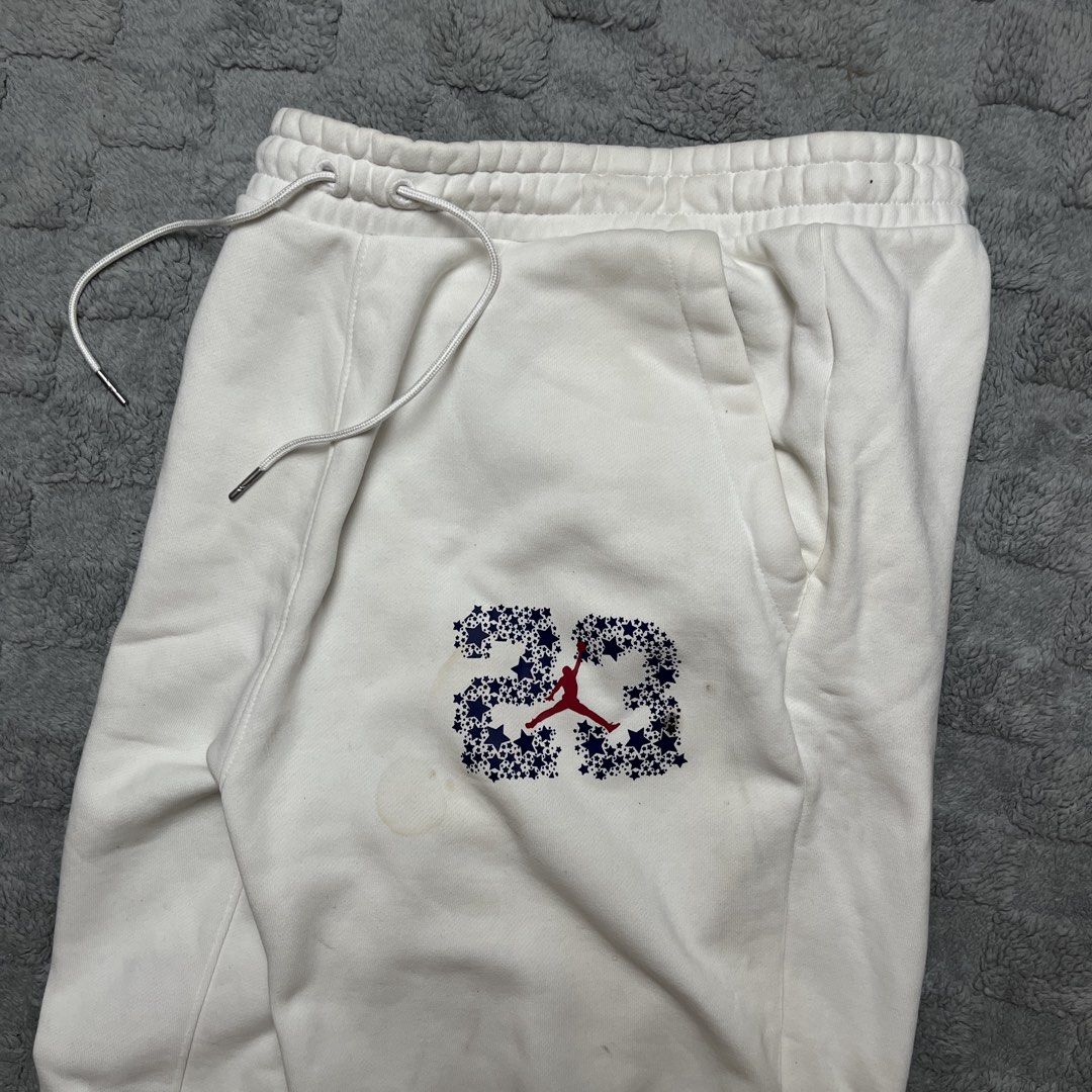 Jordan 23 White Joggers Sweatpants (Category: Joggers) located in Tarlac. Submitted by thriftspot2024 (Listing ID 1467282401, Image 2). Description: - Brand: Jordan - Size: Large - Color: White - Material: Soft fleece interior lining for maximum comfort - Design: Features signature star-filled '23' graphic and red Jumpman logo - Features: Elastic waistband, adjustable drawstrings, and ribbed ankle cuffs - Condition: Good, with a minor discolorati