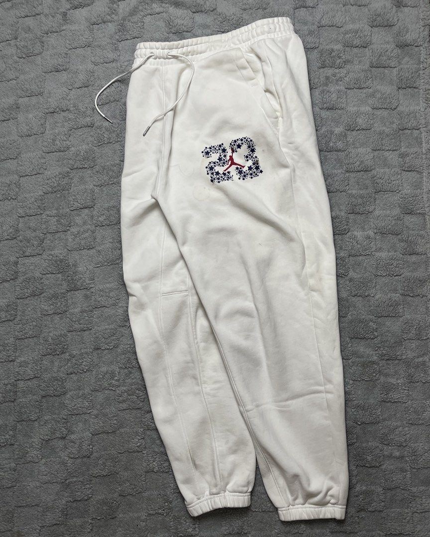 Jordan 23 White Joggers Sweatpants (Category: Joggers) located in Tarlac. Submitted by thriftspot2024 (Listing ID 1467282401, Image 1). Description: - Brand: Jordan - Size: Large - Color: White - Material: Soft fleece interior lining for maximum comfort - Design: Features signature star-filled '23' graphic and red Jumpman logo - Features: Elastic waistband, adjustable drawstrings, and ribbed ankle cuffs - Condition: Good, with a minor discolorati
