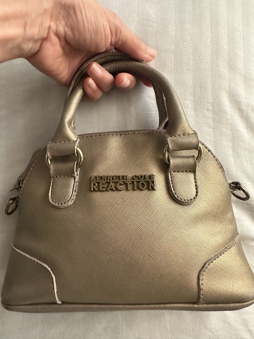 Kenneth Cole Reaction Gold Mini Handbag (Category: Luxury Bags & Wallets) located in Cebu City. Submitted by noemondragon (Listing ID 1467188845, Image 3). Description: - Kenneth Cole Reaction mini handbag in textured metallic gold. - Dome shape with dual top handles and gold-tone hardware. - Front features raised logo lettering. - Zip top closure. - Compact size for daily essentials. - Size - 9 inches x 6 inches c 3 inches - Please carefully che