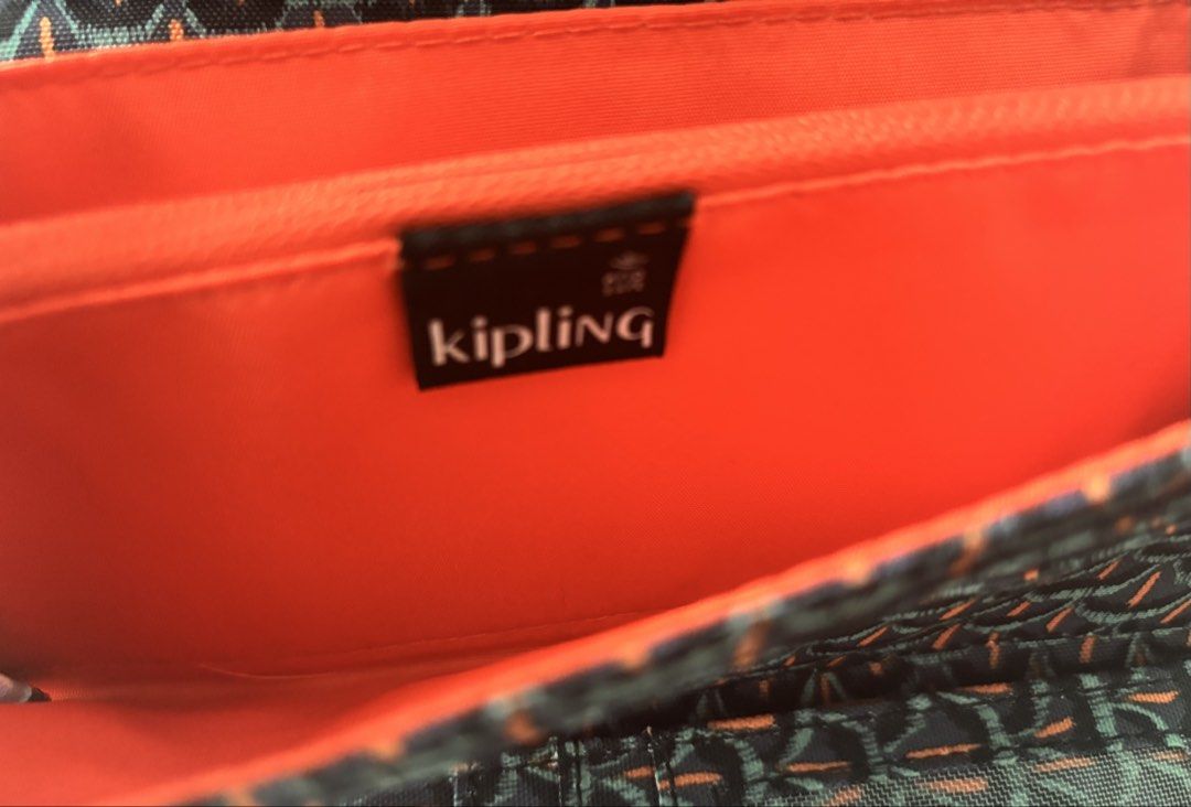 Kipling (Category: Wallets & Card Holders) located in Singapore. Submitted by vbuibui (Listing ID 1467262120, Image 4). Description: - Brand: Kipling ( Belgium) - Design: Dark patterned exterior with geometric motif and striking orange inner lining - Closure: Secure double snap-button flap - Compartments: Multiple card slots, cash compartments, and a clear ID window - bought when travelling overseas. - Condition: brand new Retail selling more tha