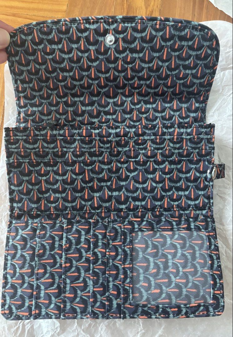 Kipling (Category: Wallets & Card Holders) located in Singapore. Submitted by vbuibui (Listing ID 1467262120, Image 3). Description: - Brand: Kipling ( Belgium) - Design: Dark patterned exterior with geometric motif and striking orange inner lining - Closure: Secure double snap-button flap - Compartments: Multiple card slots, cash compartments, and a clear ID window - bought when travelling overseas. - Condition: brand new Retail selling more tha