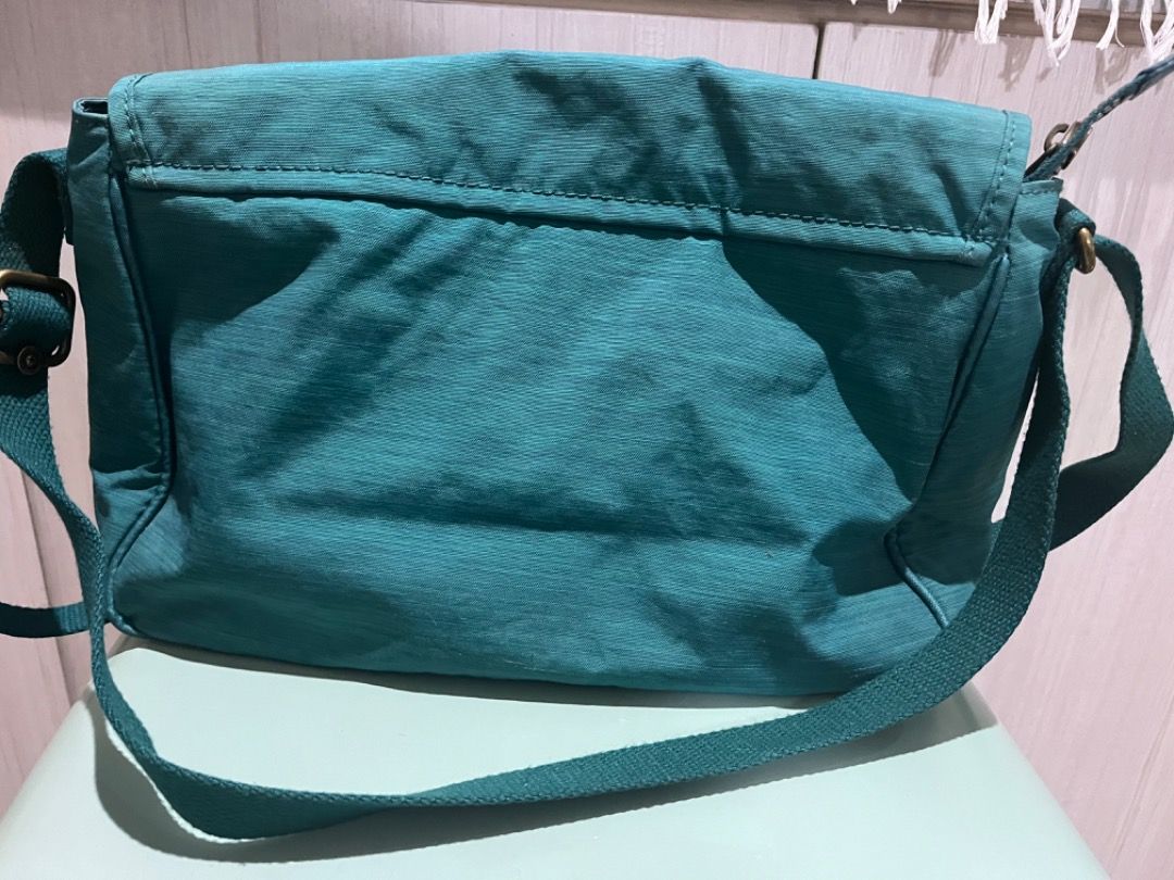 Kipling Teal Messenger Crossbody Bag with Monkey Keychain (Category: Cross-body Bags) located in Muntinlupa City. Submitted by closet_queen_13 (Listing ID 1467301623, Image 2). Description: - Authentic Kipling messenger-style crossbody bag in a vibrant teal shade - Crafted from signature durable, lightweight crinkled nylon - Secure front flap with magnetic closure - Adjustable shoulder strap for a customized fit - Inside zipper pocket and charmin