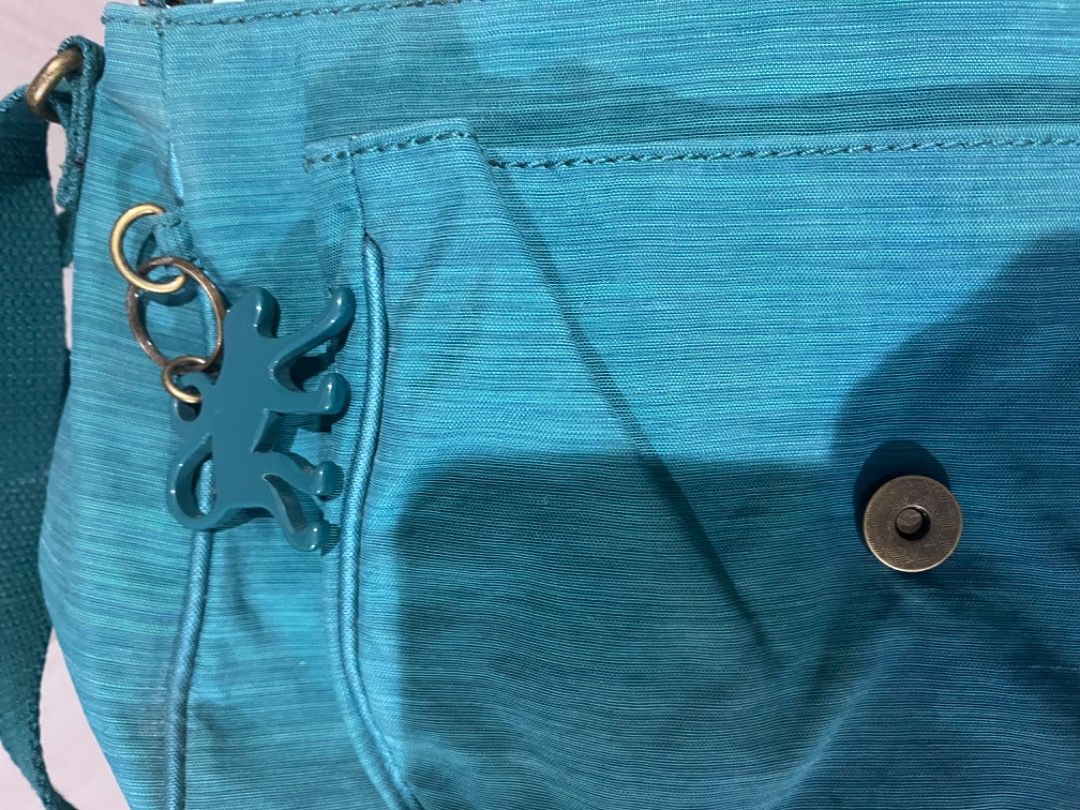 Kipling Teal Messenger Crossbody Bag with Monkey Keychain (Category: Cross-body Bags) located in Muntinlupa City. Submitted by closet_queen_13 (Listing ID 1467301623, Image 3). Description: - Authentic Kipling messenger-style crossbody bag in a vibrant teal shade - Crafted from signature durable, lightweight crinkled nylon - Secure front flap with magnetic closure - Adjustable shoulder strap for a customized fit - Inside zipper pocket and charmin