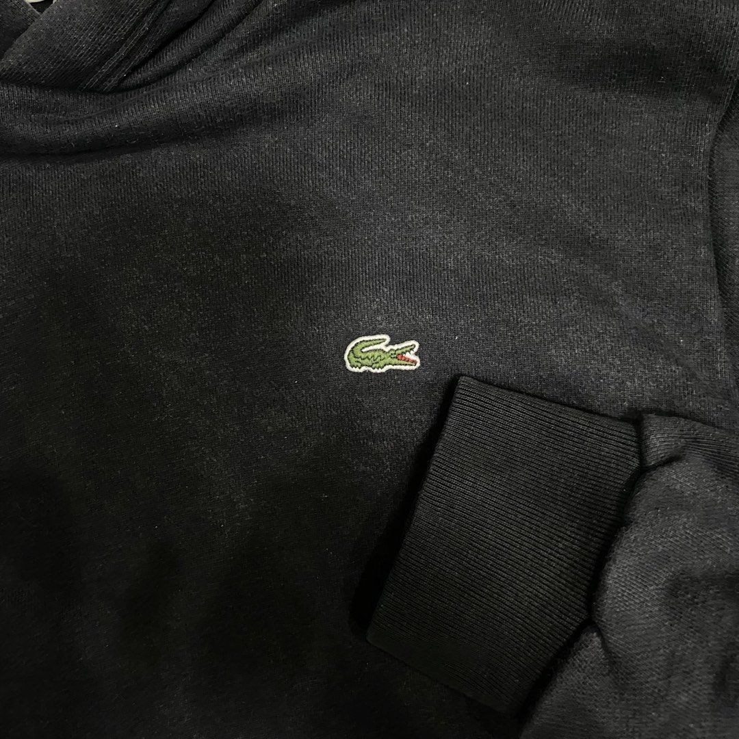 Lacoste Black Hooded Sweatshirt (Category: Coats, Jackets and Outerwear) located in Loreto, Surigao del Norte. Submitted by ongcollection_747 (Listing ID 1467330783, Image 3). Description: Classic black Lacoste hoodie with embroidered green crocodile logo on the chest. Kangaroo pocket in front, drawstring hood with metal eyelets. Cotton fabric inside. Size US M, fits true to standard medium. Tag reads French size 4. Solid everyday piece, easy to 