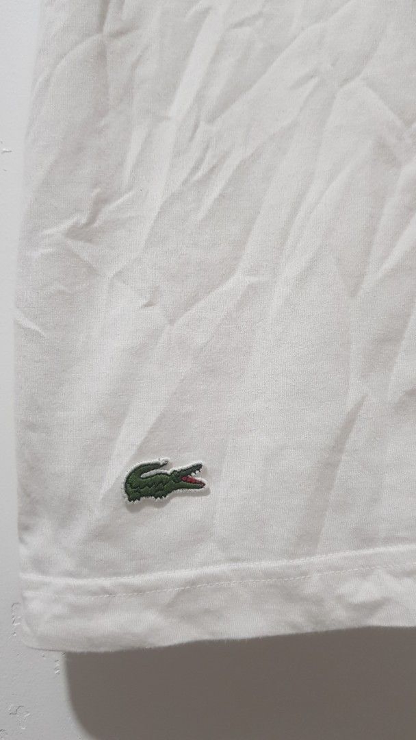Lacoste Live T-shirt Number 27 White (Category: Shirts) located in Manila. Submitted by nice430 (Listing ID 1467296313, Image 2). Description: - Brand: Lacoste Live - Color: White with navy blue sleeve stripes - Size: 2 (95cm chest measurement) - Material: 100% Cotton - Design: Crew neck with contrast collar trim, front 'Live Fast 27' print, and signature crocodile logo patch near the hem - Condition: Brand new with original neck tag and interior