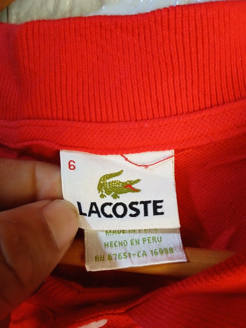 Lacoste Red Polo Shirt Size 6 (Category: Tshirts & Polo Shirts ) located in Davao. Submitted by marissasof29286 (Listing ID 1467361228, Image 3). Description: - Brand: Lacoste - Color: Bright red - Size: 6 - Material: 100% cotton - Origin: Made in Peru - Design: Classic two-button collar with embroidered green crocodile logo and standard short sleeve cut - Condition: Wrinkled from storage, needs ironing.