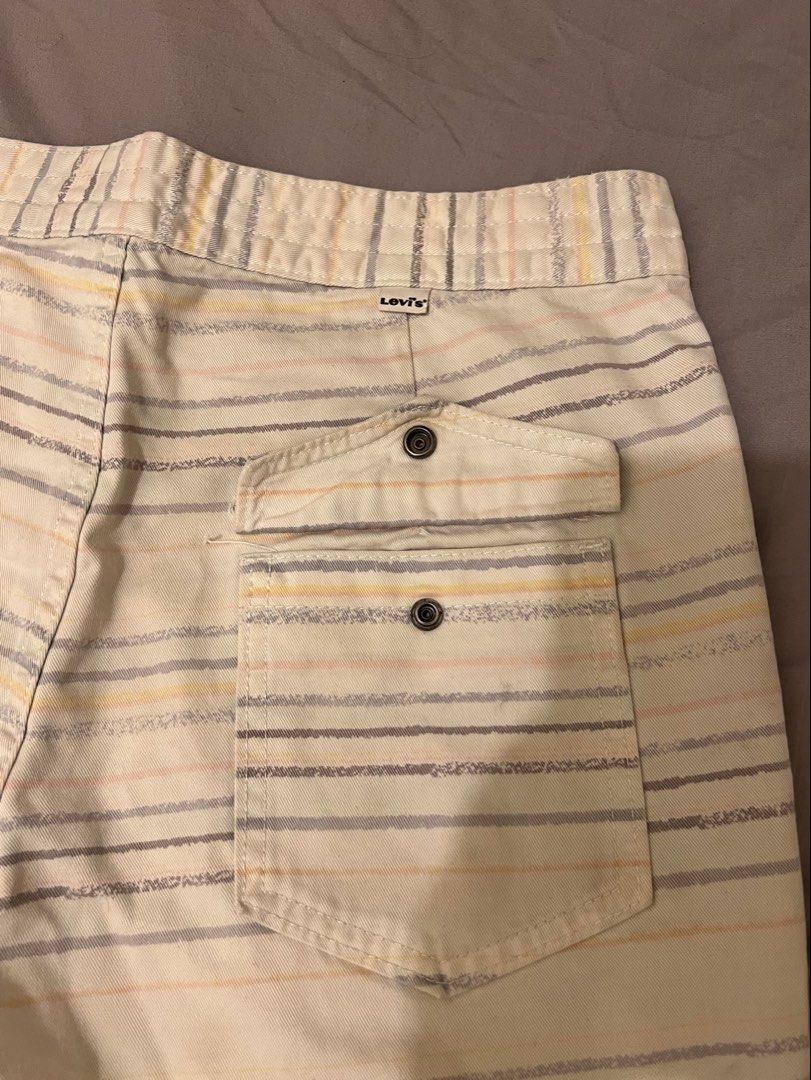 Levi's Striped Board Shorts (Category: Shorts) located in Las Pinas. Submitted by basicapparel_mnl (Listing ID 1467305476, Image 2). Description: - Brand: Levi's - Color: Cream with grey, yellow, and peach stripes - Waist: Adjustable drawstring with lace-up closure - Features: Back pocket with snap button and classic Levi's tab label - Origin: Made in China - Style: Casual summer wear, perfect for beach days or lounging.