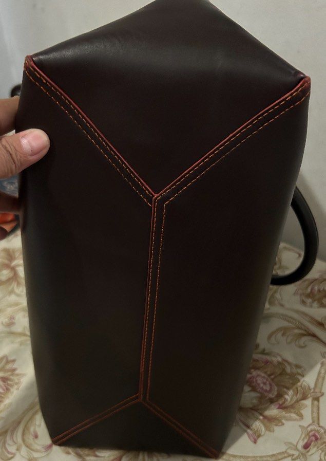 Loewe Brown and Orange Leather Tote Bag (Category: Tote Bags) located in Cavite. Submitted by honeyjmo (Listing ID 1467196261, Image 3). Description: Authentic. Loewe leather tote bag in dark brown with contrast orange interior. Sturdy top handles, gold tone hardware, embossed Anagram logo on the front. Includes a matching detachable pouch inside. Clean structure, contrast stitching along the edges, spacious main compartment. No more inclusions b