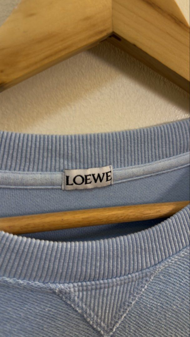Loewe Light Blue Anagram Sweatshirt (Category: Luxury Apparel) located in Paranaque City. Submitted by mykapoynton (Listing ID 1467241653, Image 3). Description: Loewe Light Blue Anagram Sweatshirt - Style: Crewneck sweatshirt - Color: Light blue with black Anagram logo - Material: 100% cotton - Origin: Made in Portugal - Size: S - Condition/Details: Comfortable fit with ribbed collar, cuffs, and hem.